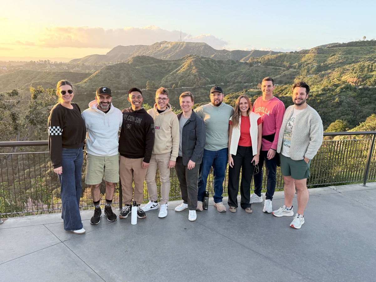 The Arrows team at a Hollywood Hills overlook at sunset, with the Hollywood sign behind them